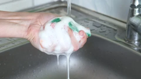 Foam from dishwashing liquid on kitchen sponge in the hand close up Stock Footage 242093143