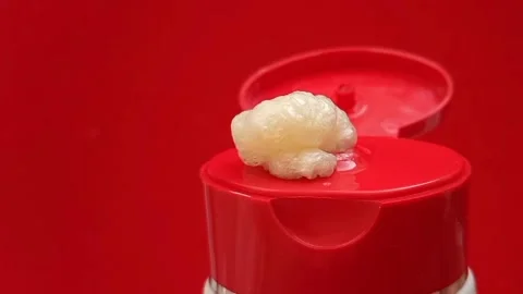 Foam face wash texture squeezed out of a tube on a red background. Cleanser  Stock Footage 321007034