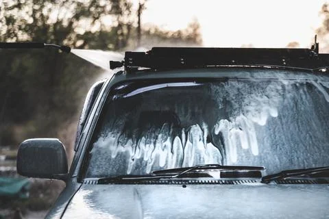 Foam flowing down the windshield of a car at a self-service car wash Stock Photos