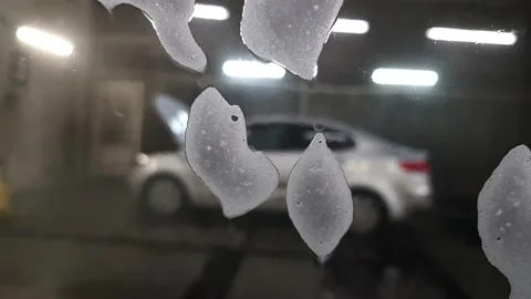 Foam flows down the glass of the car in the car wash room. Stock Footage 197466196
