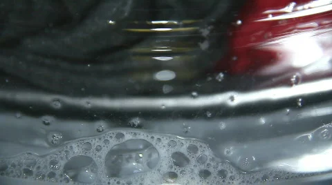 Foam flows down the glass drum of the washing machine during rotation Stock Footage 851053