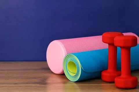 Foam roller, exercise mat and dumbbells on wooden surface promoting healthy Foto stock