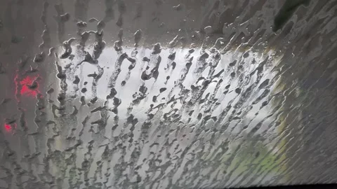 Foam slowly flowing down car windshield before powerful water rinse in auto.. Stock Footage 326438572