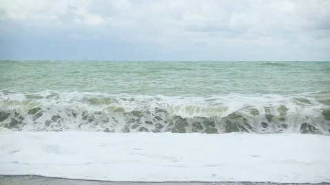 Foam from a wave rolls up a pebble beach slow mo Stock Footage 82312097