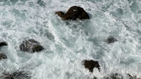 Foam of Waves Moving between black rocksTexture Background Stock Footage 89614628