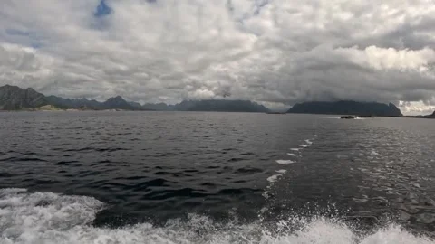 Foaming boat wake in ocean water with foggy mountain panorama Lofoten Stock-Footage 344047404