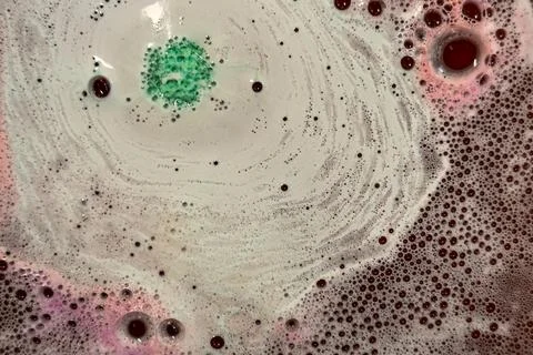 Foaming bubbles from bath bombs produce colorful spacy background plate Foto stock