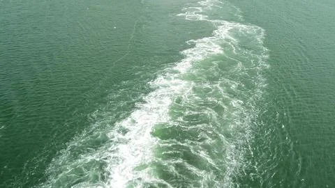 A foaming, bubbling trail on the blue surface of the water from the movement of Stock Photos