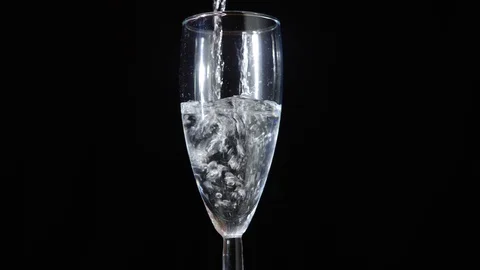 Foaming champagne in a glass on a black background. Stock Footage 80793910