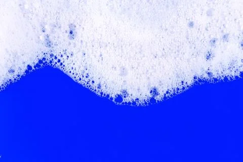 Foaming liquid on blue backdrop. Cosmetics foam background. Cosmetic produc.. Stock Photos