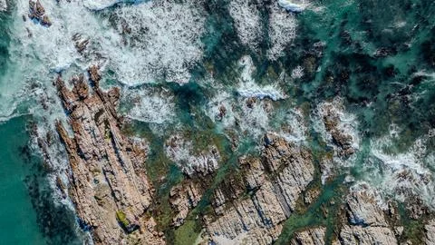 Foaming Ocean Waves Over Jagged Coastal Rocks Aerial View Stock Photos