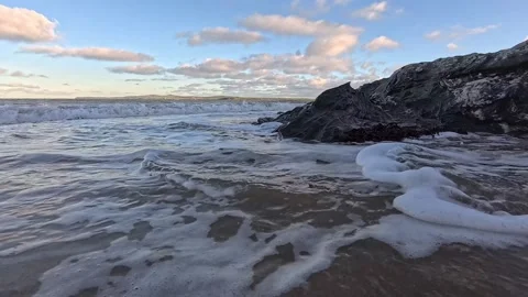Foaming ocean waves surround rocky eroded coastal beach boulder Stock Footage 325721711