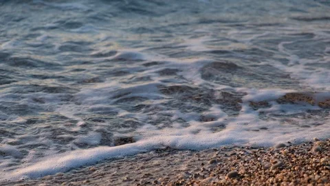 Foaming sea wave on the shore with small pebbles close-up in the evening. Stock Footage 127045631