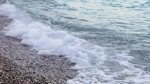 Foaming sea waves crash on a pebble beach in the evening Video stock 229548847