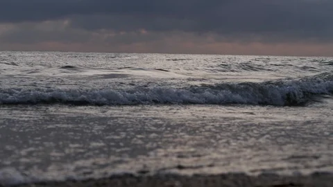 Foaming sea waves roll on sandy beach under orange sky Stock Footage 111750803