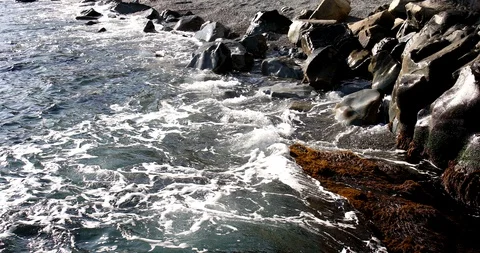 Foaming splashing background of sea waves near a rocky shore in sunny weather Stock Footage 122245711