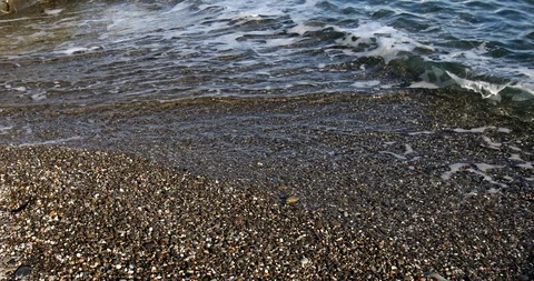 Foaming splashing background of sea waves near a rocky shore in sunny weather Stock Footage 122246229