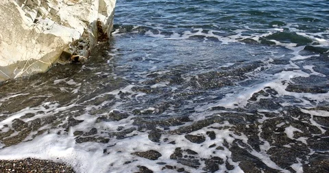Foaming splashing background of sea waves near a rocky shore in sunny weather Stock Footage 122246838