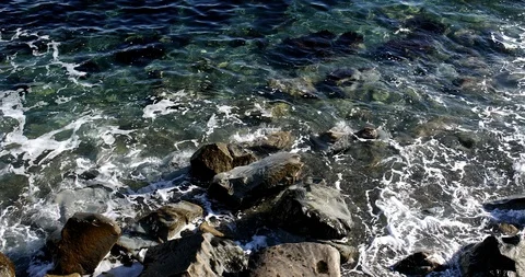 Foaming splashing background of sea waves near a rocky shore in sunny weather Stock Footage 122247074