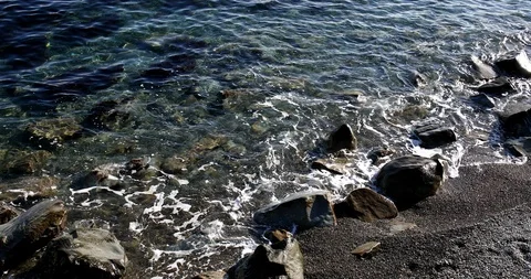 Foaming splashing background of sea waves near a rocky shore in sunny weather Stock Footage 122247182