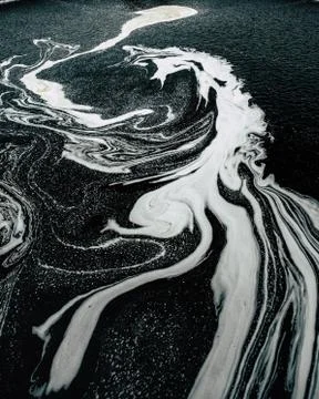 Foaming water after a waterfall creating natural art work. Stock Photos