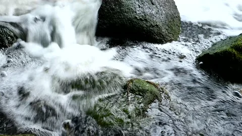 Foaming water flow between mossy rocks 動画素材 136313807