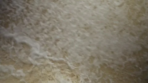 Foaming water moving over a textured sand surface Stockbeeldmateriaal 341515409