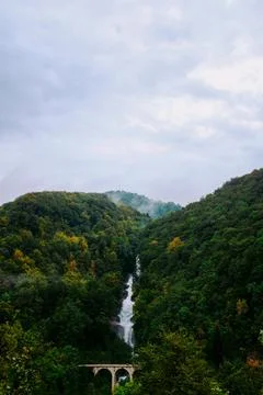 A   foaming   waterfall   drops   through   tree   covered   hills Stock Photos