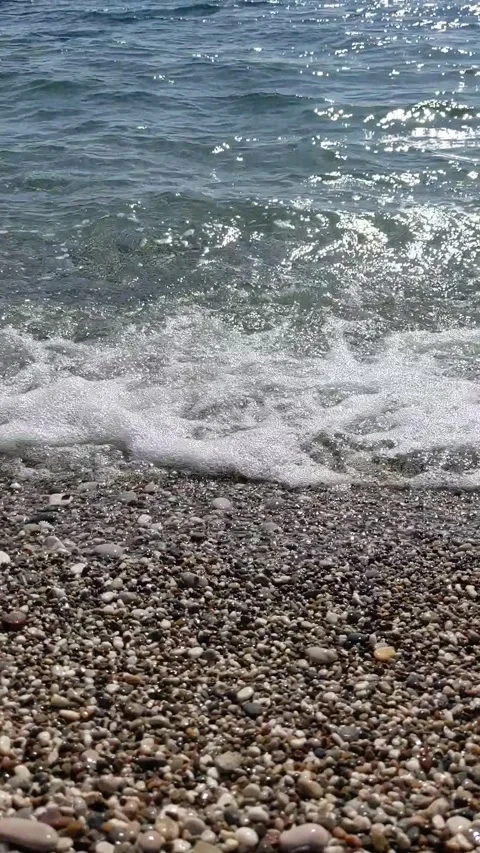 Foaming waves crash onto pebble beach. vertical video. Stock Footage 299798146