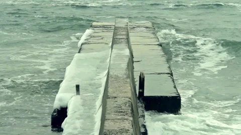 Foaming waves crashing on the ice covered pier Video stock 55424988