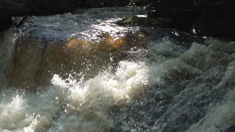 Foaming white water cascading down violently over large jagged rocks slo-mo Video stock 158512915