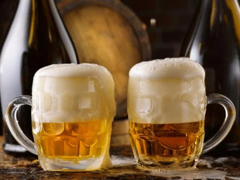 Foamy beer mugs set in rustic cellar Stock Photos