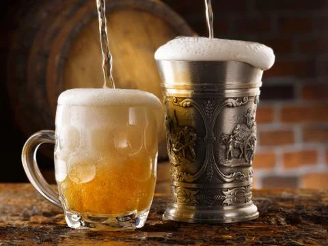 Foamy beer mugs set in rustic cellar Stock Photos