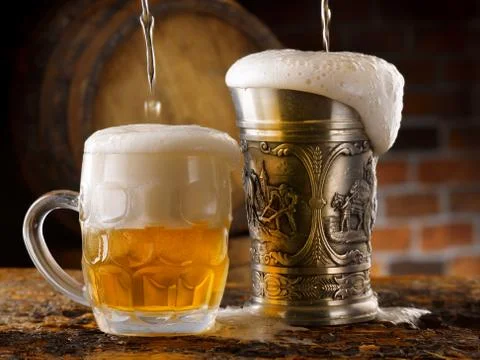 Foamy beer mugs set in rustic cellar Stock Photos