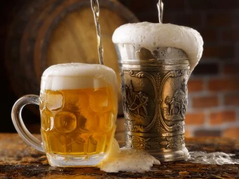 Foamy beer mugs set in rustic cellar Stock Photos