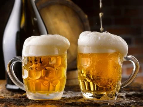 Foamy beer mugs set in rustic cellar Stock Photos