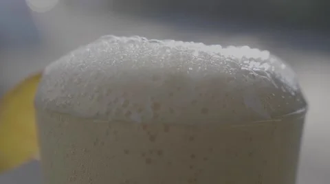 Foamy beer rises and overflows in a frosted glass with a lemon Stock Footage 64228169