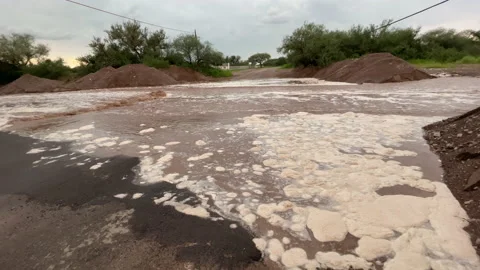 Foamy brown water from flash flood in Arizona rural street, panning Stock Footage 158633356
