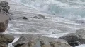 Foamy ocean waves rolling over sandy coast with rocks, power of nature, slow-mo HD Footage