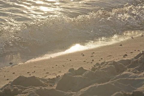 Foamy wave with bubbles hits sandy beach grains macro Stock Photos