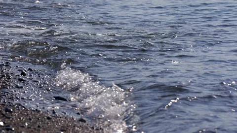 Foamy wave calmly washes pebbles on the seashore, close-up Stock Footage 324915191