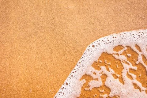 Foamy wave on sandy beach Stock Photos