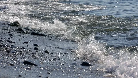 Foamy wave washes over pebbles to the sound of the surf Stock Footage 324920639