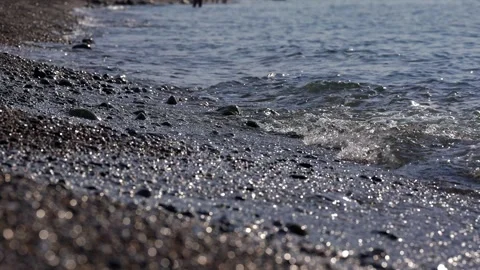 Foamy wave washes over pebbles to the peaceful sound of the surf. Video stock 324920640