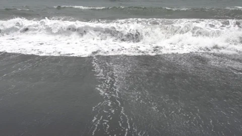 Foamy waves on the black sand beach in cloudy weather. Stock Footage 104404042
