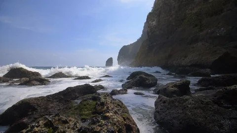 Foamy waves breaking over rocks by the Indonesian coastline Stock Footage 93781676