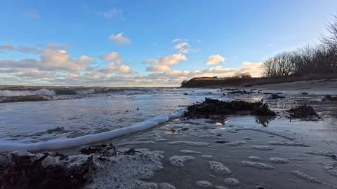 Foamy waves cover mirror reflecting sandy welsh beach at twilight Stock Footage 325722408