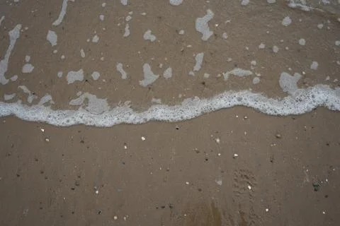 Foamy Waves On Sandy Beach With Pebbles, Llanddwyn Beach, Anglesey, North Wales. Stock Photos