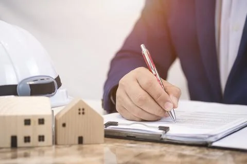 Focus at architect's hand signing document on marble table in office room Stock Photos