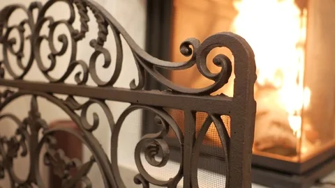 Focus changes from curved iron fireguard to flame blazing in fireplace 스톡 동영상 72633424